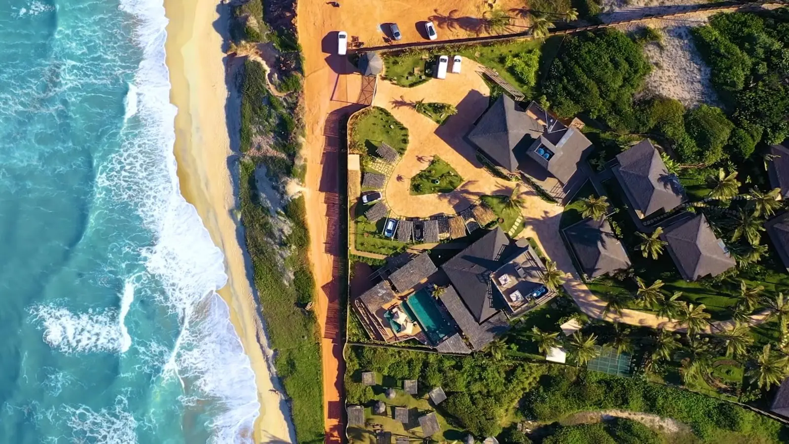 Aerial view of Filha da Lua's thatched bungalows and pool above Praia das Minas beach near Pipa
