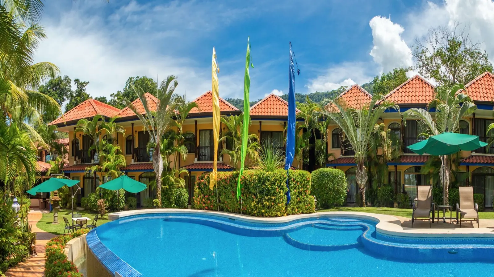 Pool and garden in front of the red-roofed buildings at Hotel Cuna del Angel